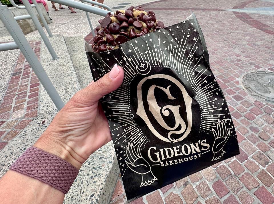 hand holding a bag with a gideon's chocolate chip cookie