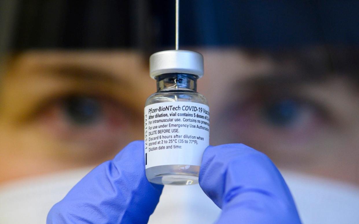 A doctor holds an injection vial with the Corona vaccine in the vaccination center for employees at the municipal hospital in Dresden, Germany - DPA