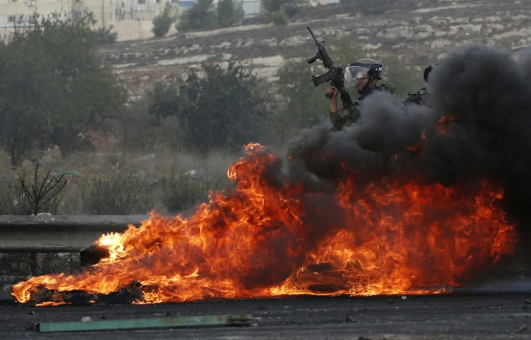 Israeli security forces stand behind burning tires during clashes with Palestinians near the Beit El Jewish settlement in the occupied West Bank, on October 9, 2015