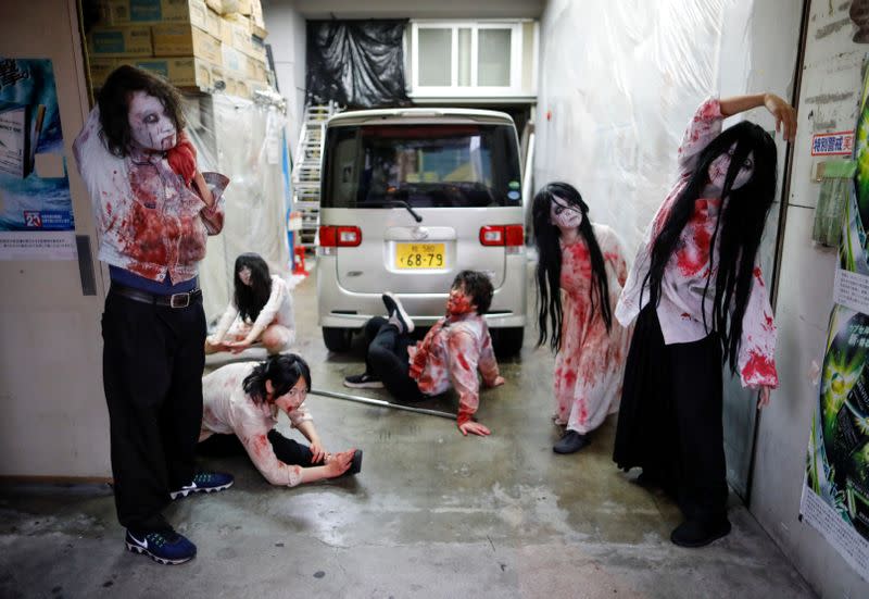 Actors dressed as zombies or ghouls stretch before their performance at a drive-in haunted house show, performed by Kowagarasetai, for people inside a car in order to maintain social distancing amid the spread of the coronavirus disease (COVID-19), in Tok