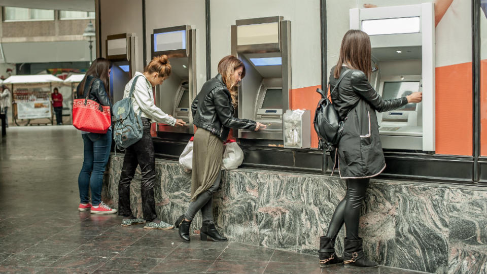 edit Four girl friends withdrawing money from credit card at ATM