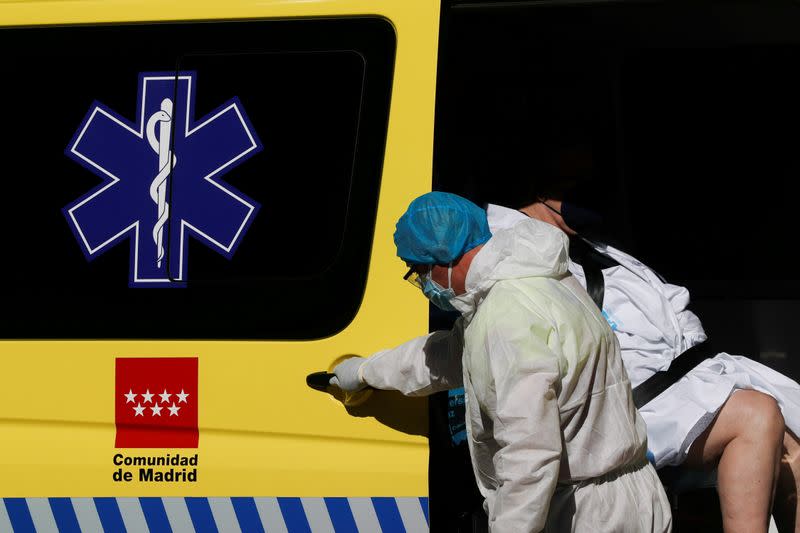 FILE PHOTO: A healthcare worker in protective gear assists a patient into an ambulance outside the emergency unit of the Hospital Universitario La Paz during the coronavirus disease (COVID-19) outbreak in Madrid
