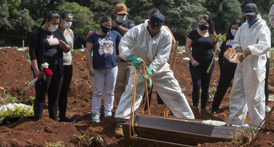 Men bury coffin at cemetery as family members look on. Source: AP