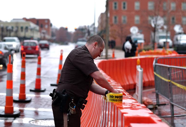 A police officer puts tape on barricades around the Buzz Westfall Justice Center in Clayton, Missouri, on November 23, 2014 where a grand jury has been considering whether to indict a white police officer who shot and killed a black teenager