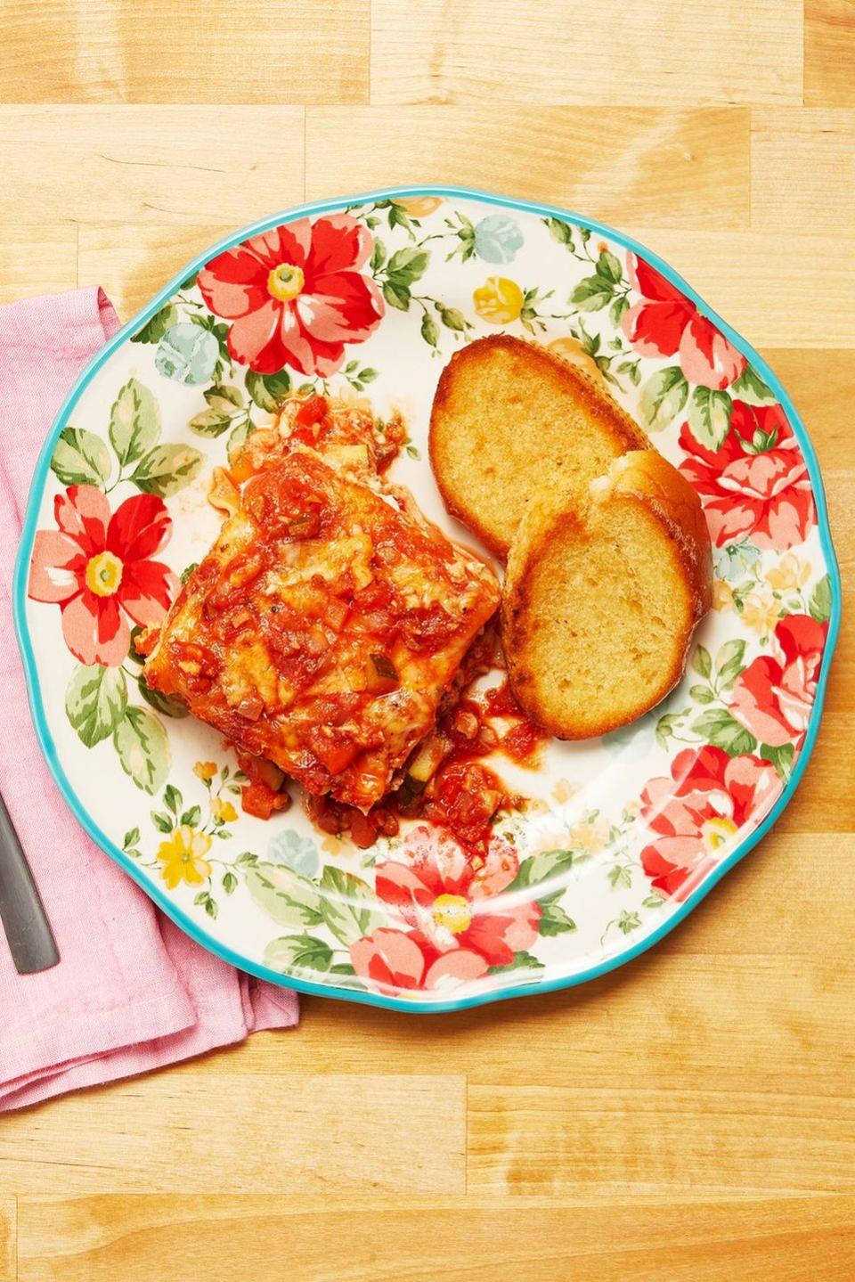 vegetable lasagna slice on floral plate with bread