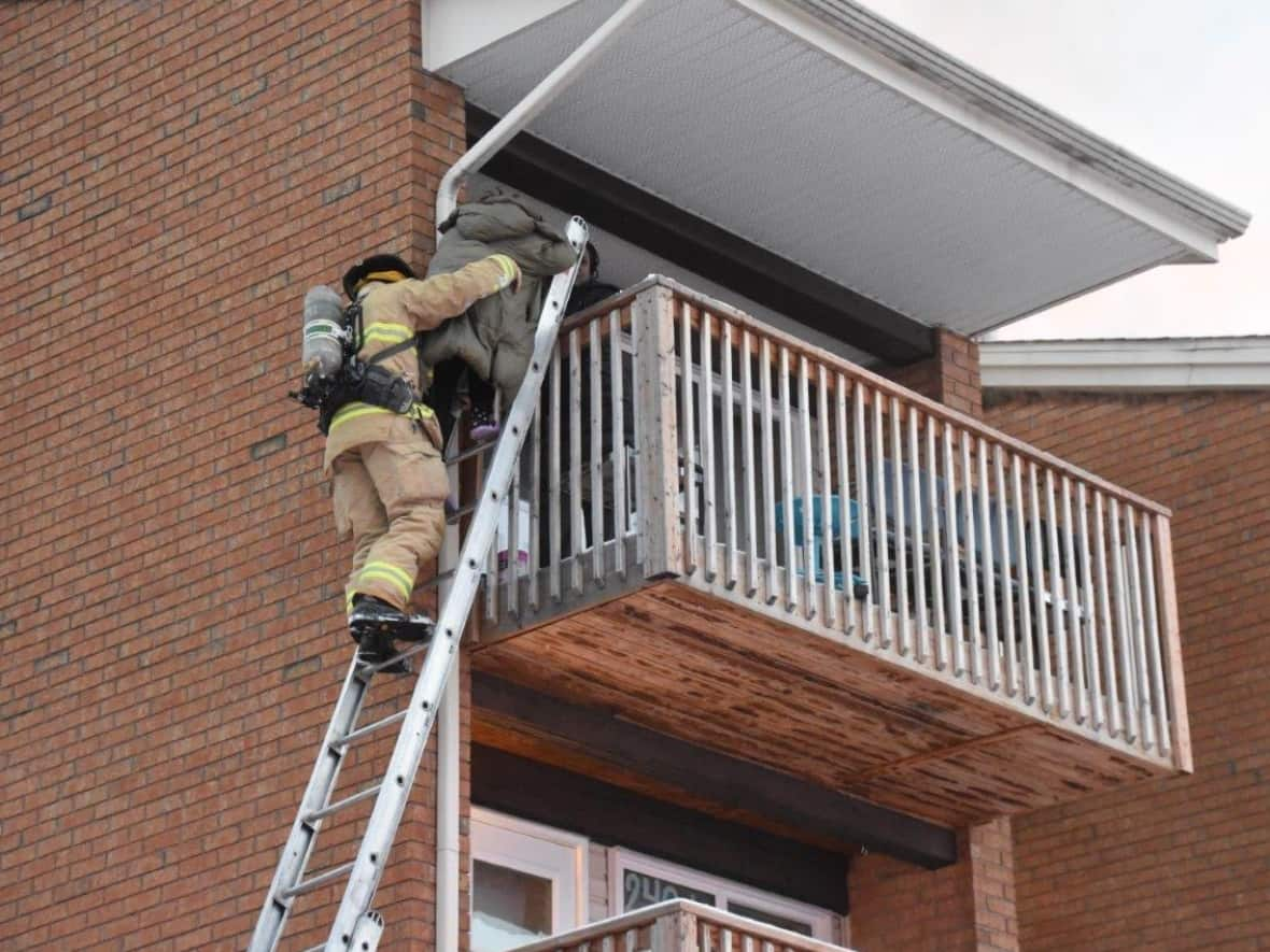 Ottawa firefighters rescue a child from an apartment building that was on fire Feb. 21, 2023. Four people were rescued, they said. (Jean Lalonde/Ottawa Fire Services - image credit)