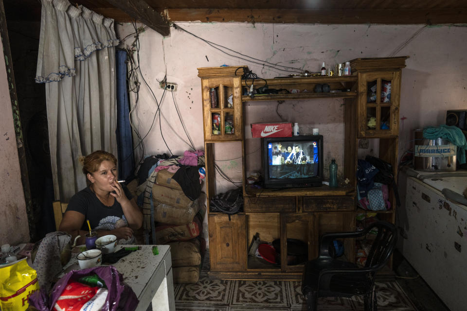 Soledad Campos, 37, smokes a cigarette inside her home where police detained her 18-year-old son Nicolas Campos as a suspect in connection with the sale of contaminated cocaine in the Puerta 8 suburb north of Buenos Aires, Argentina, Friday, Feb. 4, 2022. A batch of cocaine has killed at least 23 people and hospitalized many more in Argentina, according to police. (AP Photo/Rodrigo Abd)