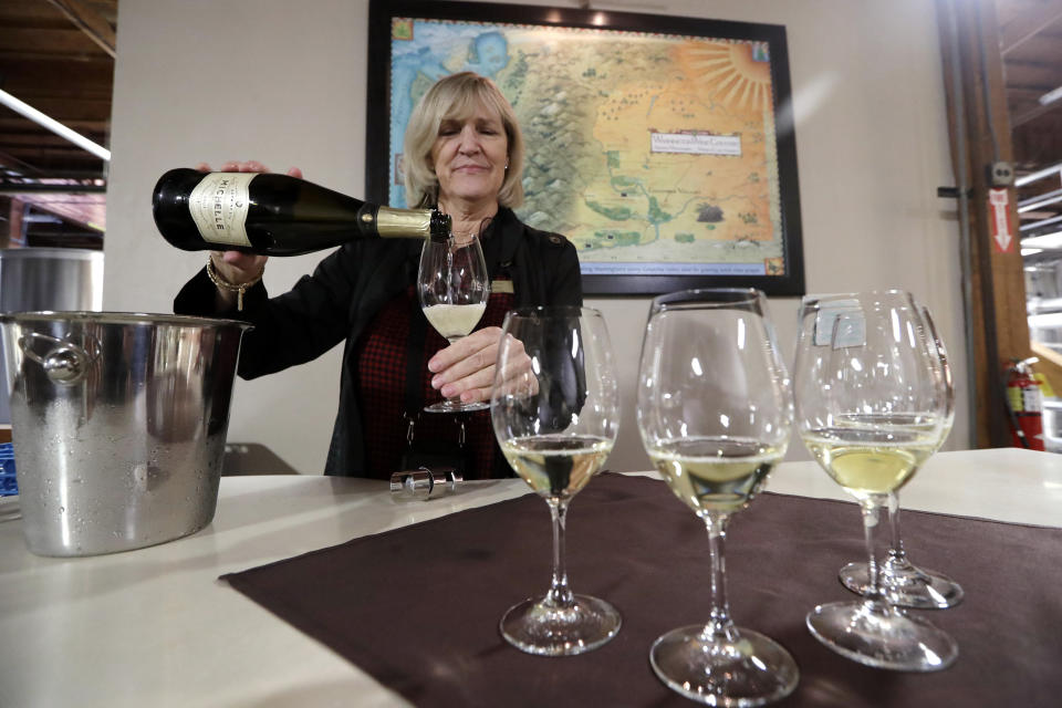 In this photo taken Thursday, Nov. 21, 2019, guest services representative Ginny Swanstrom pours a sparkling wine for a tour group to taste at Chateau Ste. Michelle winery in Woodinville, Wash. From less than 20 wineries in 1981, the Washington wine industry has grown to more than 1,000 this year. The state is the second-largest producer of premium wines in the U.S., trailing only California. (AP Photo/Elaine Thompson)