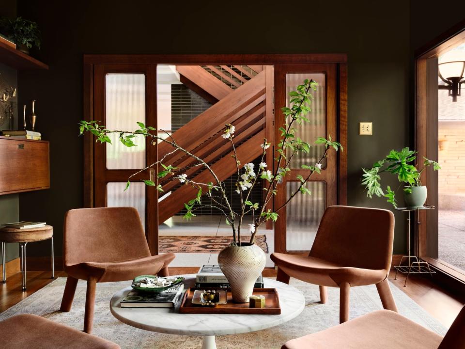 A green room with brown furniture and large plants.