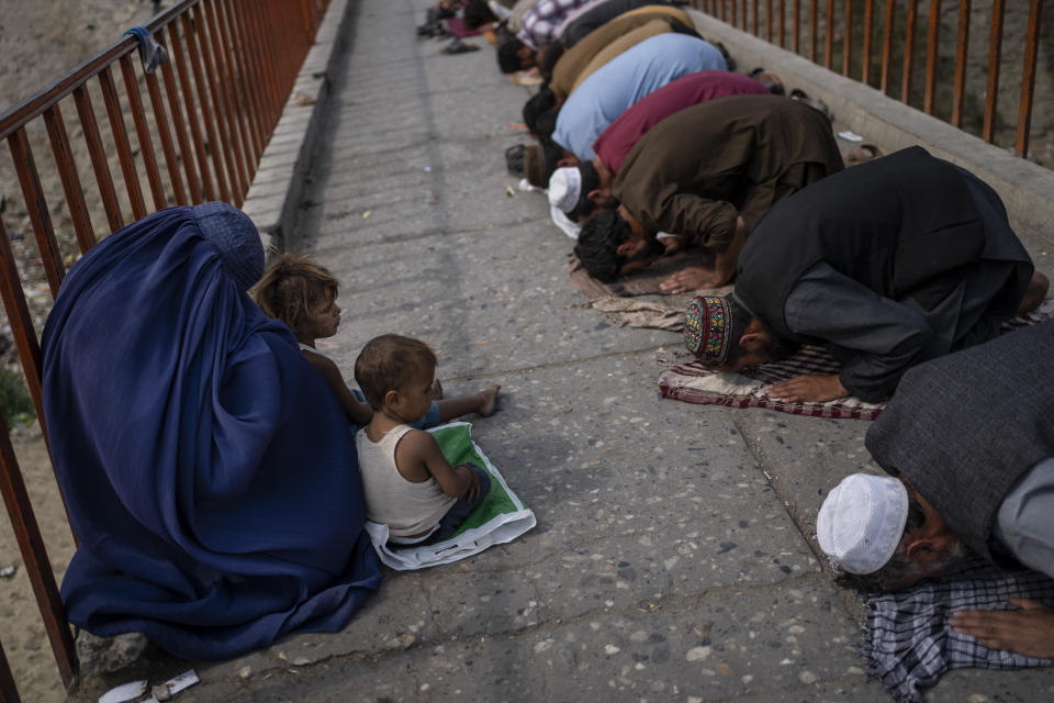 A burqa-clad Afghan woman and two children beg for alms during Friday prayers in Kabul, Afghanistan, Friday, Sept. 24, 2021. (AP Photo/Bernat Armangue)