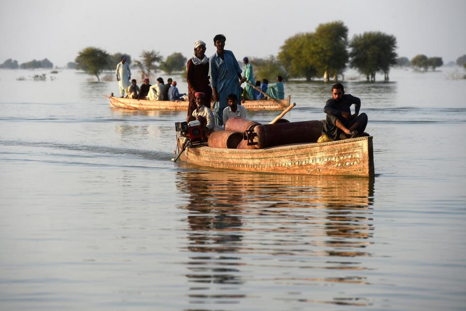 Internally displaced people use boats to cross a flooded area at Dadu in Sindh province on October 27, 2022. (Photo by Asif HASSAN / AFP) (Photo by ASIF HASSAN/AFP via Getty Images)