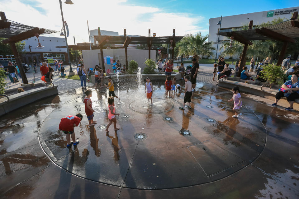 Children play in a splash pad at the evening farmers market presented by the Farmers and Crafts Market of Las Cruces in Downtown Las Cruces on Wednesday, June 12, 2019.