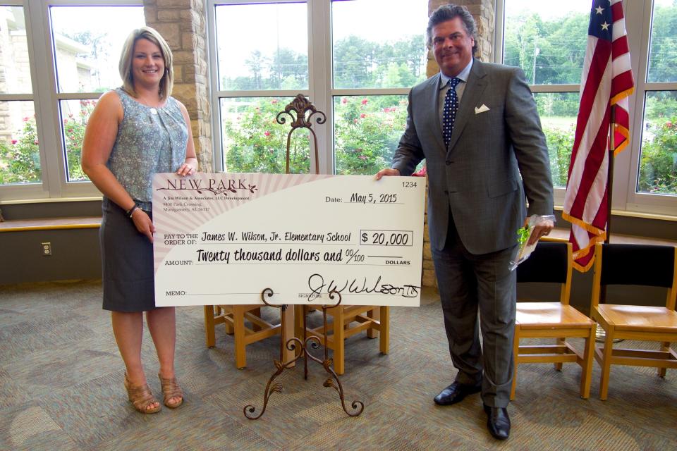 Wilson Elementary School Principal Meredith Bishop and Jim Wilson III stand with a check representing a donation made to the school from Jim Wilson and Associates in 2015.