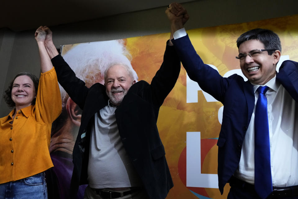 Brazil's former President Luiz Inacio Lula da Silva, center, holds hands up with Senator Randolfe Rodrigues, right, and Workers' Party President Gleisi Hoffmann as he arrives to a meeting with leaders of the Rede Sustainability Party in Brasilia, Brazil, Thursday, April 28, 2022. The conference brings together leftist political parties to discuss strategies and policy platforms in anticipation of Oct. elections. (AP Photo/Eraldo Peres)