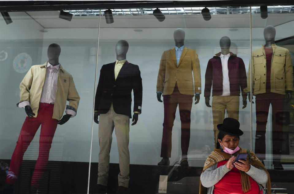 A woman talks on her cellphone in front of a men's clothing store in La Paz, Bolivia, Tuesday, April 11, 2023. (AP Photo/Juan Karita)