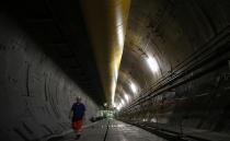 An engineer walks inside a Turin-Lyon high-speed rail tunnel (TAV) in Saint Martin La Porte, France, Tuesday, Feb. 12, 2019. The project is part of an European wide network to improve high-speed rail connections. On the Italian side, the construction site long targeted by sabotaging protesters is guarded by four law enforcement agencies and has been reduced to maintenance work only. The survival of Italy's increasingly uneasy populist government could very well depend on whether Italy restarts construction on the TAV link, which it halted in June. (AP Photo/Antonio Calanni)