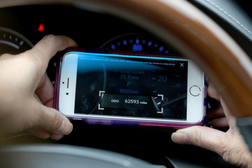 Person taking a photo of a car's mileage reading on their smart phone