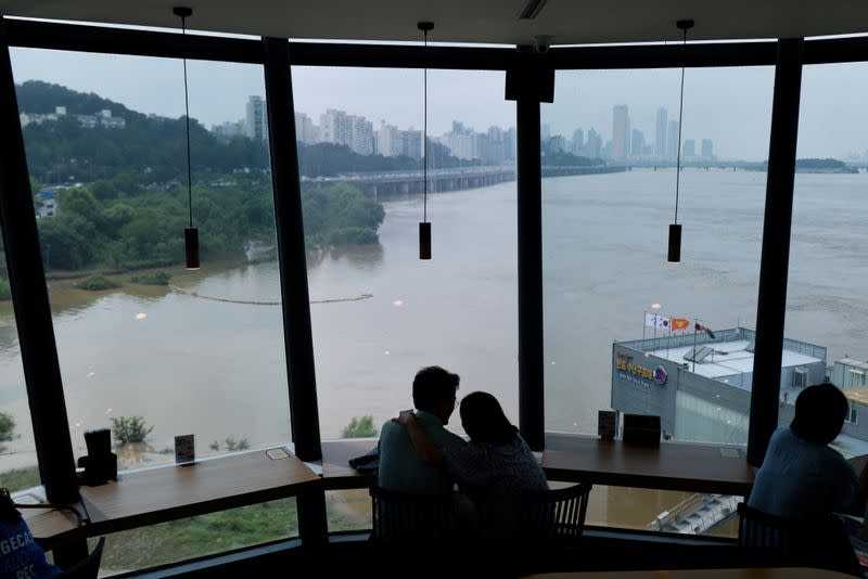 A couple looks at a flooded Han River park in Seoul