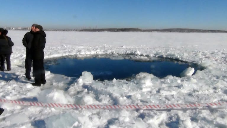 People stand near a six-metre (20-foot) hole in the ice of a frozen lake, reportedly the site of a meteor fall, outside the town of Chebakul in the Chelyabinsk region on February 15, 2013