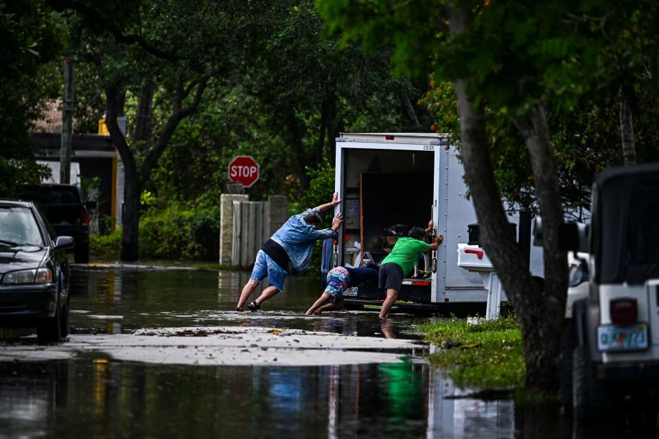 People pushing a truck through water on a street