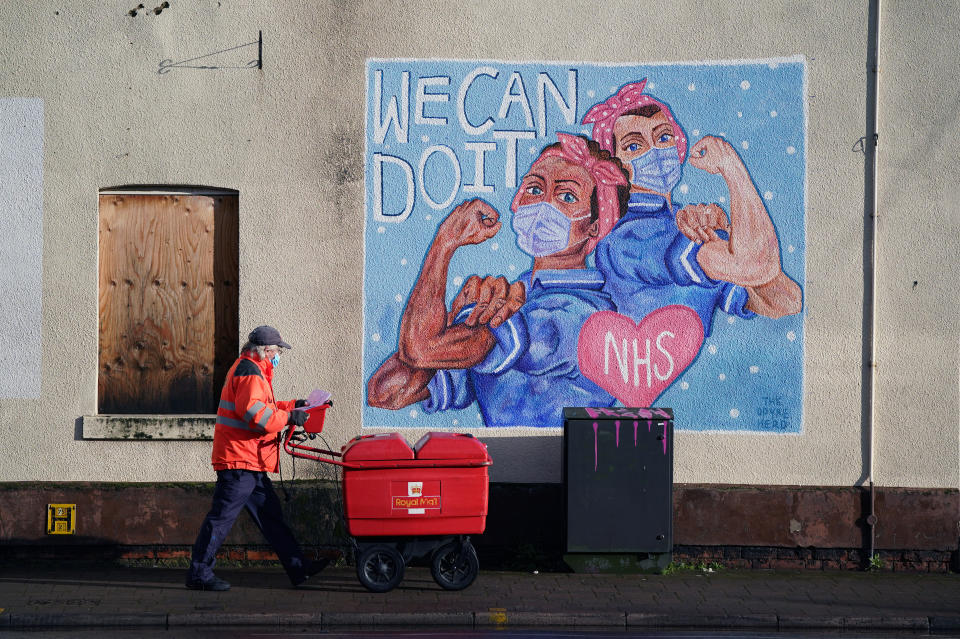 A Royal Mail delivery worker passes an NHS Mural in Loughborough, Leicestershire, during England's third national lockdown to curb the spread of coronavirus. (Photo by Zac Goodwin/PA Images via Getty Images)