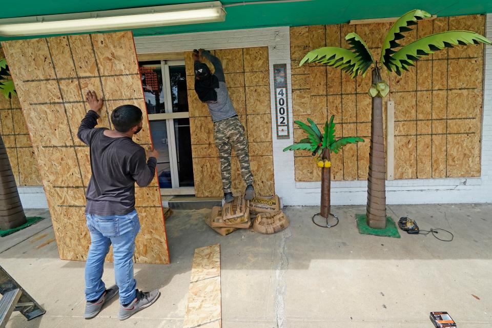 Issac Alvarado, right, and Kevin Enriquez board up windows on Tuesday at Bayside Chic, a coastal decor store in Galveston, Texas, ahead of Hurricane Laura's arrival in the Gulf Coast.