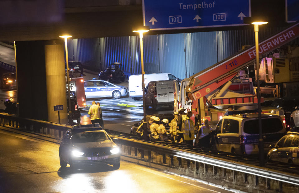 Forensic experts are investigating a car at the city motorway A100 after an accident in Berlin, Germany, Tuesday, Aug. 18, 2020. According to German news agency dpa, prosecutors say the series of crashes caused by a 30-year-old Iraqi man on the highway was an Islamic extremist attack. (Paul Zinken/dpa via AP)