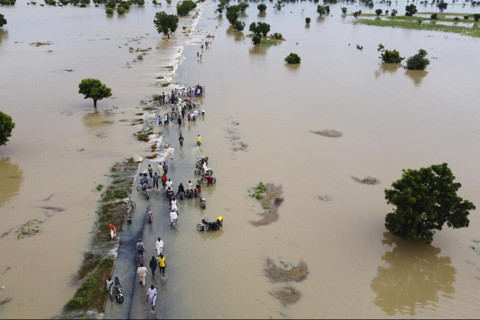 People walk through floodwaters after heavy rainfall in Hadeja, Nigeria, Monday, Sept 19, 2022. Elections, coups, disease outbreaks and extreme weather are some of the main events that occurred across Africa in 2022. Experts say the climate crisis is hitting Africa “first and hardest.” Kevin Mugenya, a senior food security advisor for Mercy Corps said the continent of 54 countries and 1.3 billion people is facing “a catastrophic global food crisis” that “will worsen if actors do not act quickly.” (AP Photo)