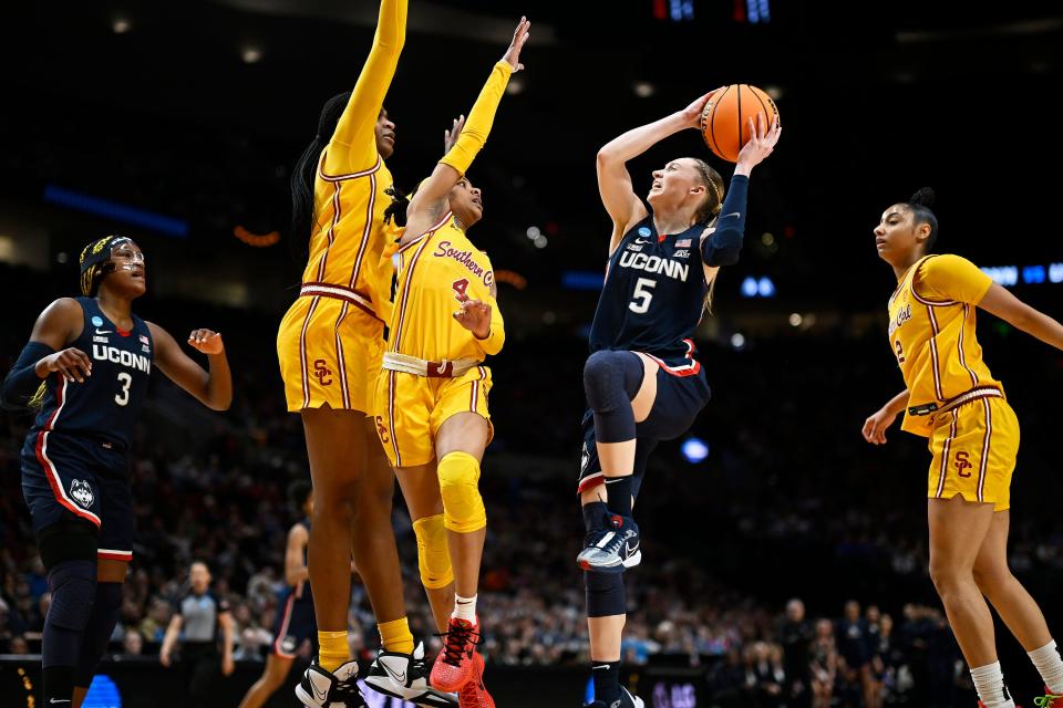 UConn Huskies guard Paige Bueckers (5) drives to the basket against USC Trojans guard Kayla Williams (4) and center Clarice Akunwafo (34) during the Elite Eight of the Portland Regional.