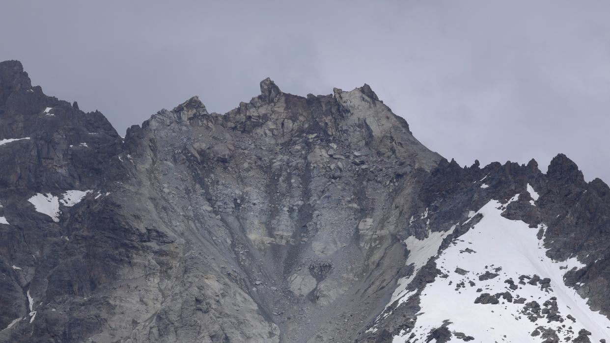  the remains of the peak of a mountain in the swiss alps , with snow covered sides and a landslide in the center 