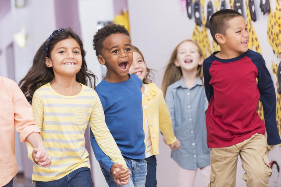 Group of young kids laugh and smile while holding hands