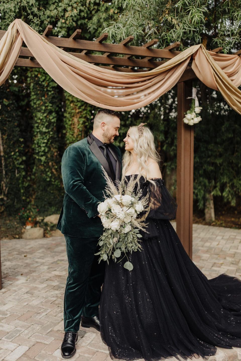 A bride and groom look at each other in front of their wedding altar.