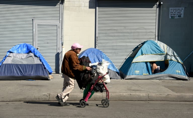 A woman pushes her walker past tents housing the homeless in Los Angeles, California on February 9, 2016