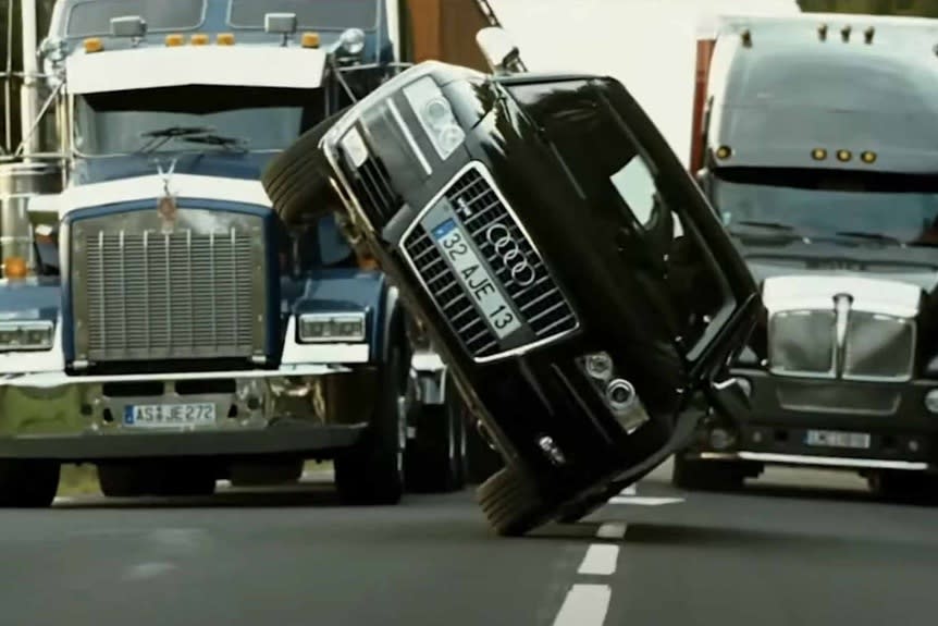 A car drives sideways between two trucks in Transporter 3 (2008).