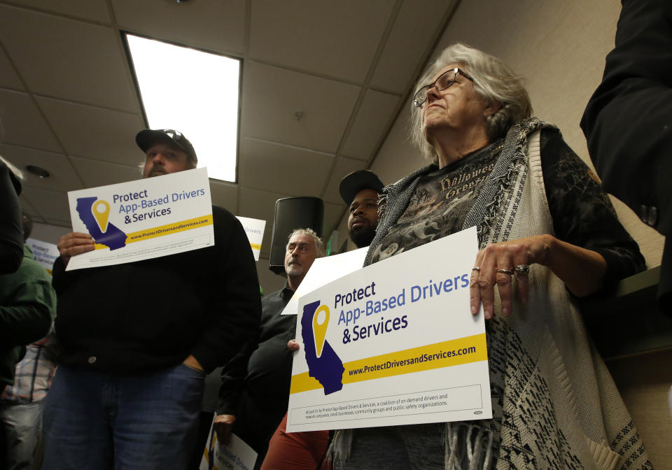 FILE — In this Oct. 29, 2019, file photo, Carla Shrive, right, who drives for various gig companies, joined other drivers to support a proposed ballot initiative challenging a recently signed law that makes it harder for companies to label workers as independent contractors, in Sacramento, Calif. Uber, Lyft and DoorDash have said they'll spend $30 million to put an initiative on the 2020 ballot to overturn the law. (AP Photo/Rich Pedroncelli, File)