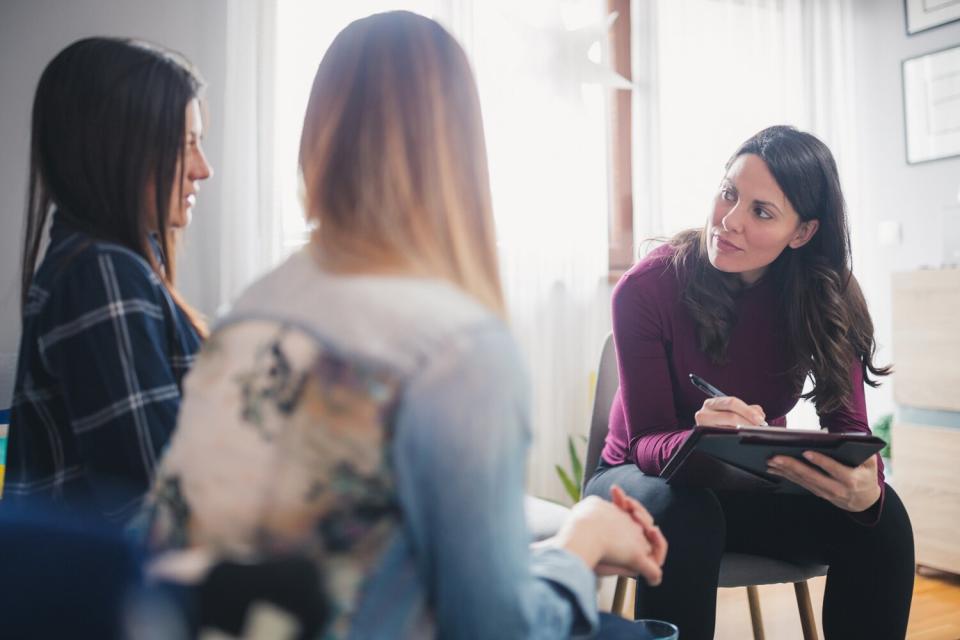 Pregnant counselor advising young lesbian couple at their home