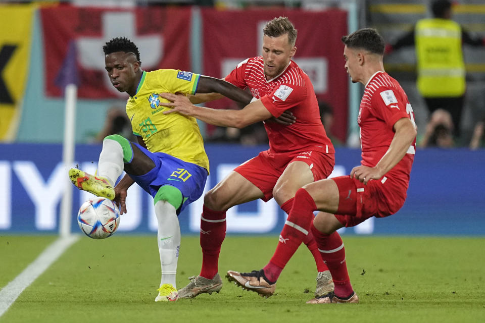 El brasileño Vinicius Junior (izquierda) pugna por el balón con los suizos Silvan Widmer (centro) y Fabian Rieder durante el partido por el Grupo G del Mundial, el lunes 28 de noviembre de 2022, en Doha, Qatar. (AP Foto/Ariel Schalit)