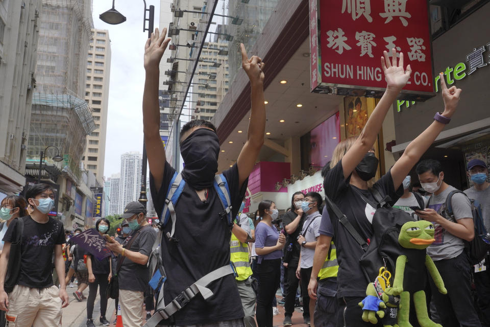 Protesters gesture with five fingers, signifying the "Five demands - not one less" as they march along a downtown street during a pro-democracy protest against Beijing's national security legislation in Hong Kong, Sunday, May 24, 2020. Hong Kong's pro-democracy camp has sharply criticised China's move to enact national security legislation in the semi-autonomous territory. They say it goes against the "one country, two systems" framework that promises the city freedoms not found on the mainland. (AP Photo/Vincent Yu)