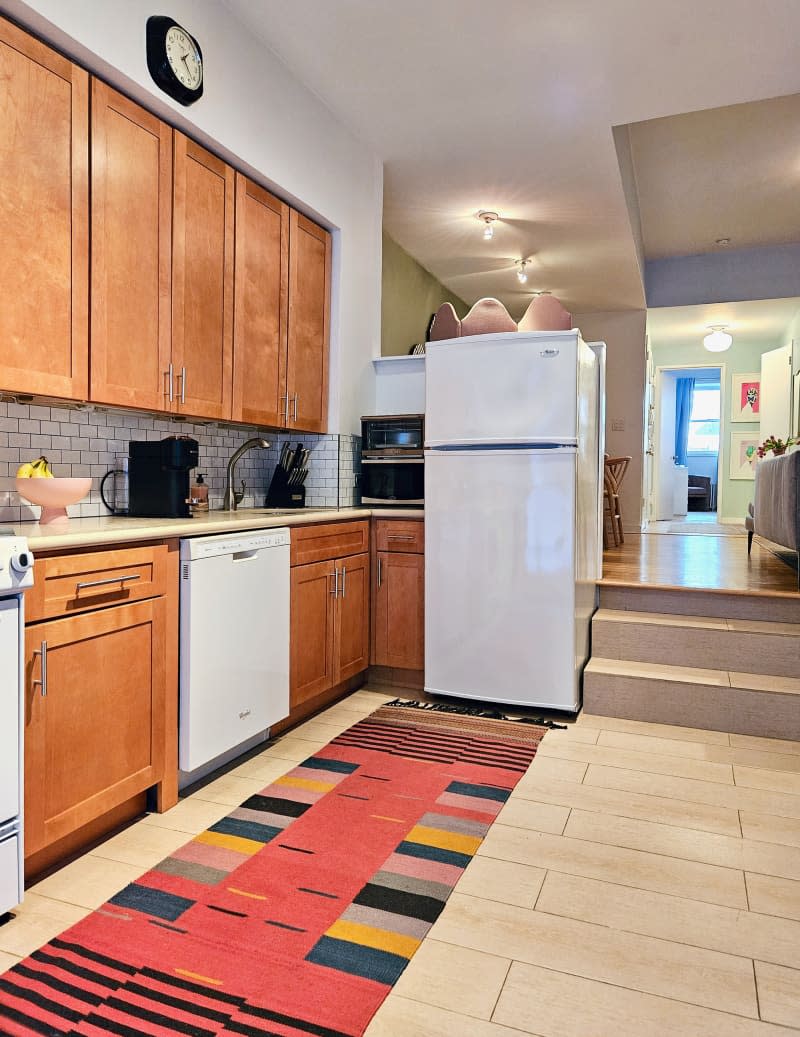 White kitchen with colorful geometric pattern runner and wood cabinets