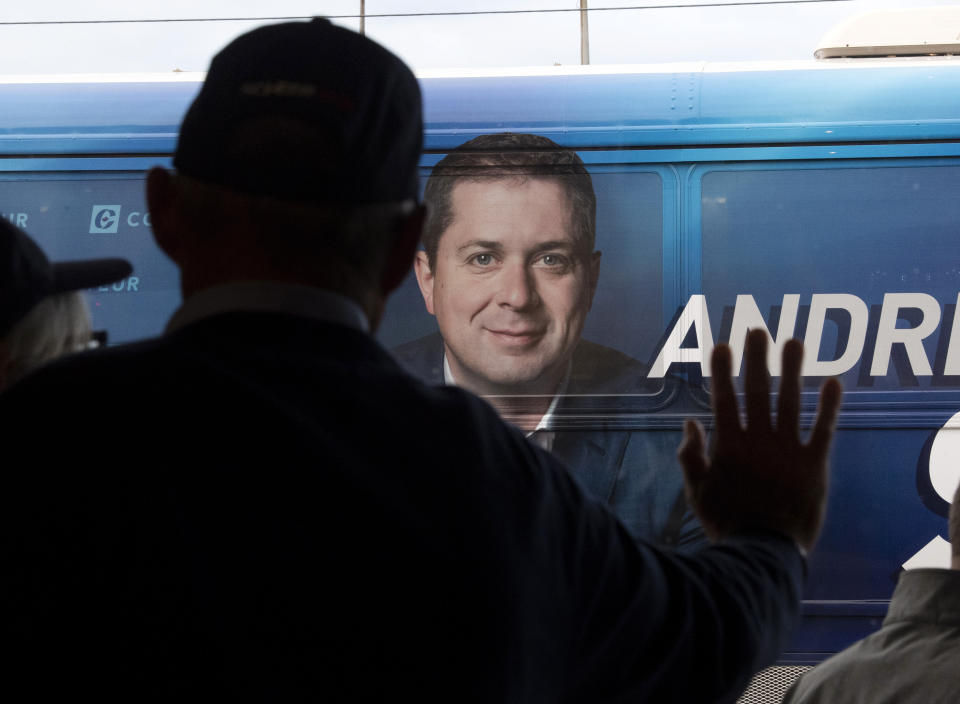 FILE - In this Oct. 16, 2019, file photo, a supporter leans on a window as Conservative leader Andrew Scheer's bus arrives at a campaign stop in Hamilton, Ontario. Polls show that Scheer has a chance to defeat Justin Trudeau's Liberal party in national elections on Monday, Oct. 21. (Adrian Wyld/The Canadian Press via AP, File)