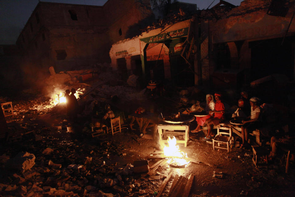 <p>Earthquake survivors sit around a fire in downtown Port-au-Prince, Friday, Feb. 5, 2010. (Photo: Rodrigo Abd/AP) </p>