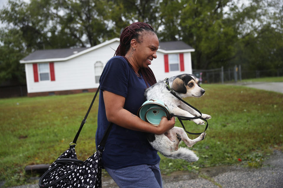 FAYETTEVILLE, NC - SEPTEMBER 16: Dominique Capers carries her dog Lougie as she evacuates her home ahead of possible flood waters after Hurricane Florence passed through the area on September 16, 2018 in Fayetteville, North Carolina.&nbsp;
