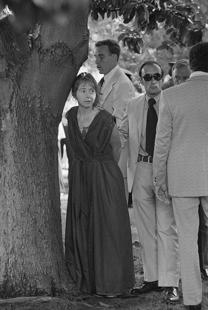 Lynette Fromme standing by a tree with men in suits standing by her