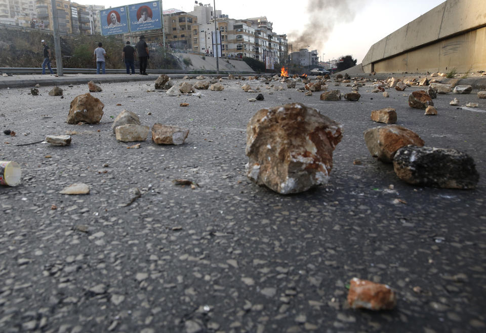 Protesters close a main highway with stones and burning tires during ongoing protests against corruption and politicians in Khaldeh, south of Beirut Lebanon, Wednesday, Nov. 13, 2019. A local official for a political party was shot dead by soldiers trying to open a road closed by protesters in southern Beirut late Tuesday, the army reported, marking the first death in 27 days of nationwide protests. (AP Photo/Hussein Malla)