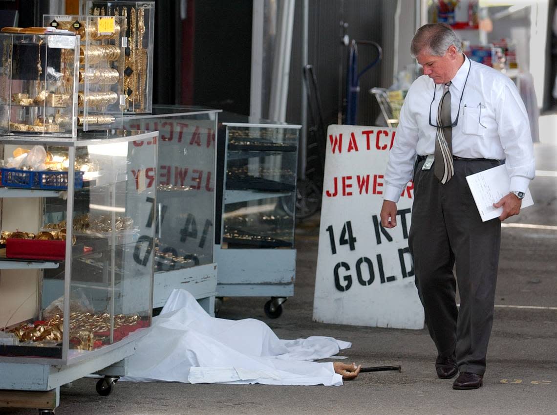 A Miami-Dade homicide detective inspects the scene where jewelry vendors Jonada and Angela Campos were shot to death during a robbery at the Opa-locka Hialeah Flea Market in 2003.