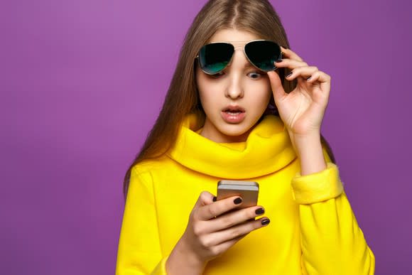 A surprised woman checking her phone.