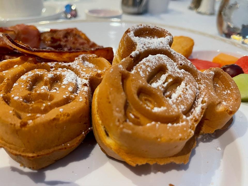 Mickey-shaped waffles on a plate with powdered sugar on top