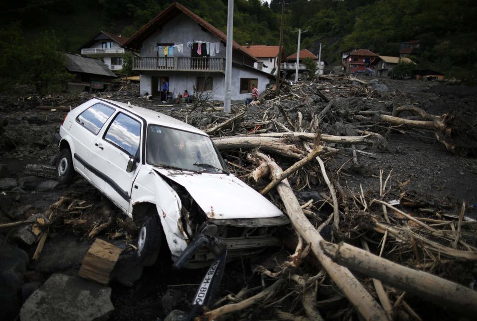 A damaged car sits in front of flood-damaged houses in Topcic Polje