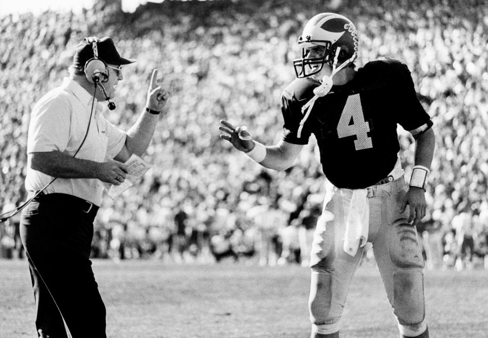 Michigan Wolverines head coach Bo Schembechler (left) confers with quarterback Jim Harbaugh (4) during the 1986 Sunkist Fiesta Bowl against the Nebraska Cornhuskers at Sun Devil Stadium.