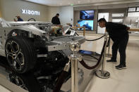 Visitors to the Xiaomi Automobile flagship store look at the interiors of a Xiaomi SU7 electric car on display in Beijing, Tuesday, March 26, 2024. Chinese smartphone maker Xiaomi announced that it will deliver its first electric vehicle on March 28, 2024. (AP Photo/Ng Han Guan)